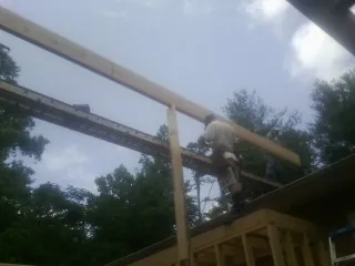Carpenter setting a ridge beam over a new addition frame — Ice Dam Removal by Roofing Brothers in Littleton