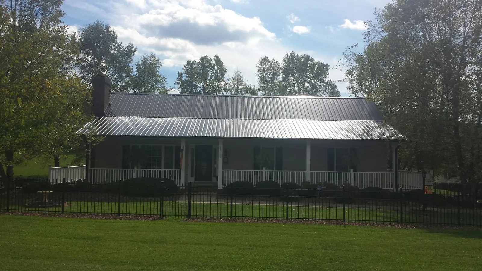 Gray metal roof on a brick ranch with a full width front porch — Gutter Guard Installation work by our crew in Littleton